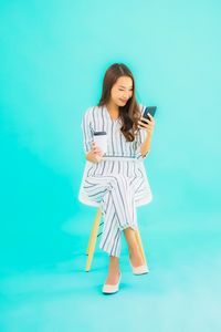 Young woman using smart phone against blue background