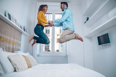 Man and woman jumping on bed at home