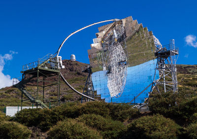 Low angle view of traditional windmill on field against clear blue sky