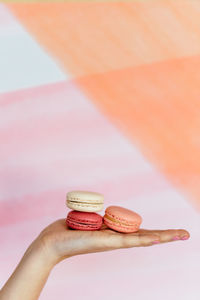 Close-up of hand holding macarons against blurred background