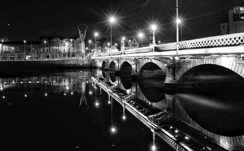 Illuminated bridge over river at night