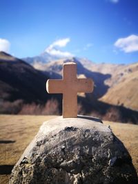 Close-up of cross on mountain against sky