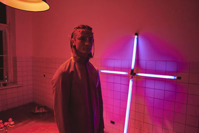 Young man standing in illuminated room