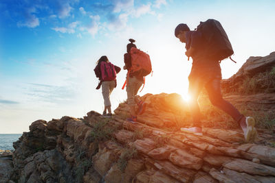 Hikers walking on rocky mountain against sky