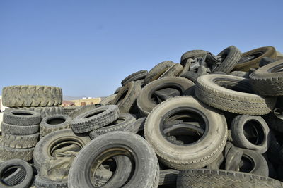 Low angle view of tire stack against clear blue sky