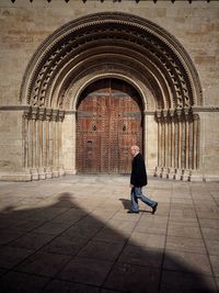 Side view of man walking against valencia cathedral door