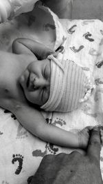 Cropped hand of man touching newborn baby sleeping on bed