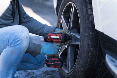 A man changes a wheel on a car, a seasonal change of rubber on a car