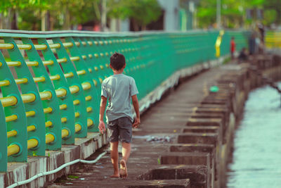 Rear view of man walking on footpath sea