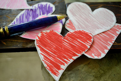 Close-up of papers hearts and pen on table