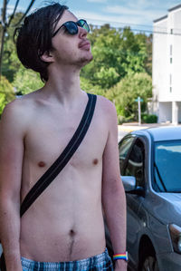 Midsection of shirtless man standing in car