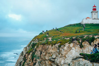 Scenic view of sea by mountain against sky