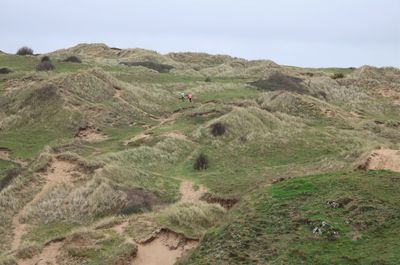Scenic view of lone woman in sand dunes against sky