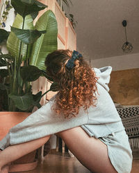 Rear view of woman with curly hair at home - ayla eulalia