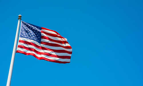 Low angle view of american flag against clear blue sky