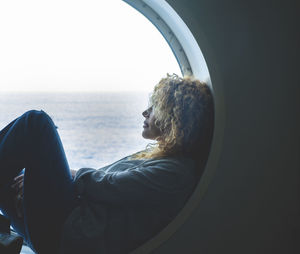 Rear view of woman looking through window