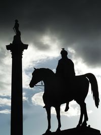 Low angle view of silhouette statue against cloudy sky