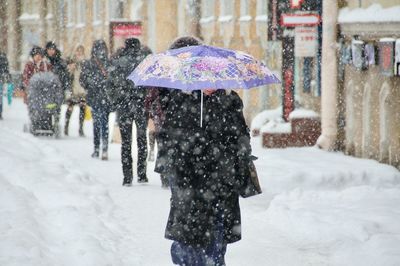 Rear view of woman walking in snow during winter