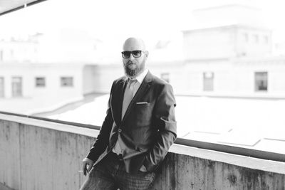 Portrait of man wearing sunglasses standing against building in city