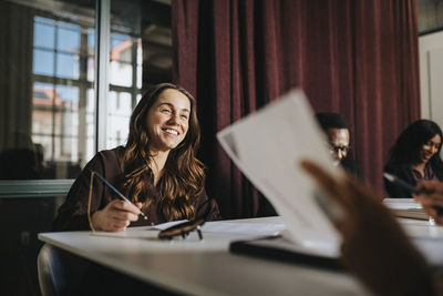 Smiling businesswoman discussing with colleague during meeting in board room at office