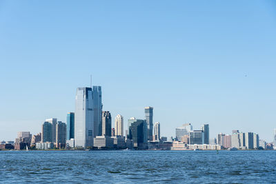 Sea by buildings against clear sky