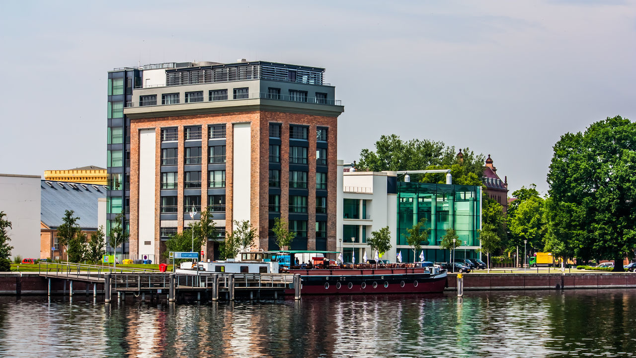 BUILDINGS BY RIVER AGAINST SKY