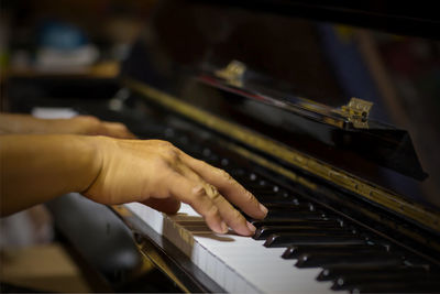 Cropped hands of man playing grand piano