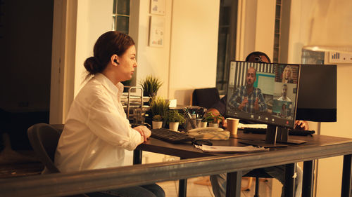 Side view of young woman sitting on table