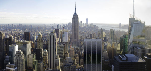 Empire state building in city against sky