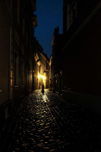 Illuminated street amidst buildings in city at night