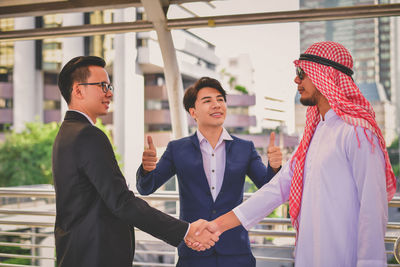 Businessman shaking hands while colleague gesturing on elevated road
