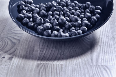 Blueberries or bilberries in blue plate on table,  blue berries , monochrome  , healthy eating