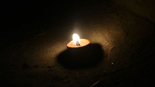 Close-up of lit candle in darkroom