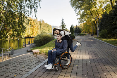 Woman embracing disabled man on wheelchair from behind