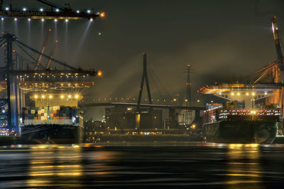 Container ships moored in illuminated dock at night