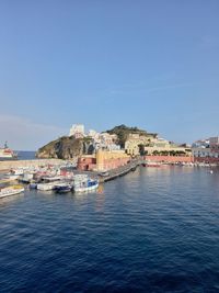 Buildings by sea against clear blue sky