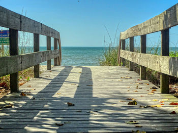 Wooden walkway by sea against clear sky