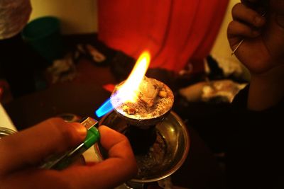 Cropped image of person igniting coal in hookah