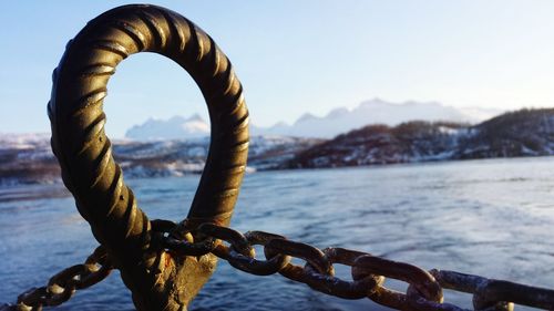 Chain on metallic bollard against lake