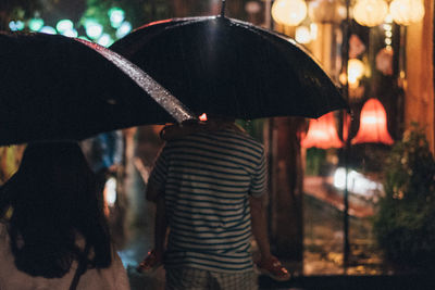 Rear view of people on wet street during rainy season