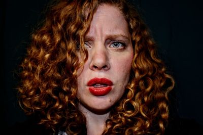 Close-up portrait of woman against black background