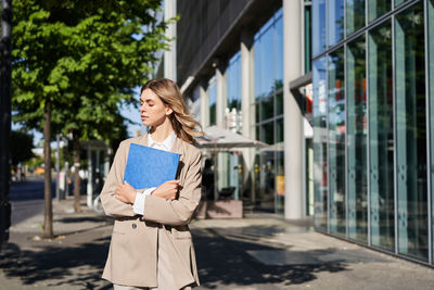 Portrait of young woman standing in city