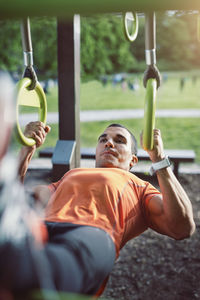 Man hanging with rings and doing chin-ups