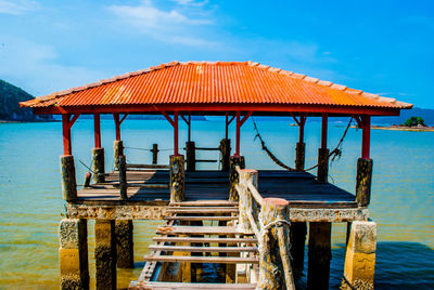 Stilt house in sea against sky