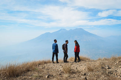 Friends standing on mountain against sky