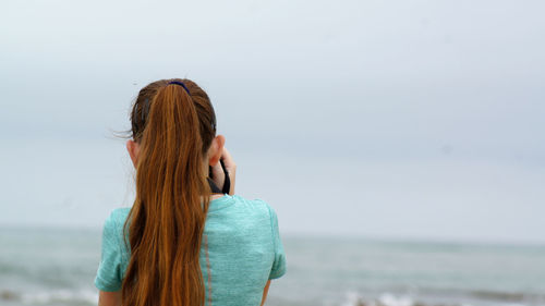 Rear view of girl looking at beach against sky