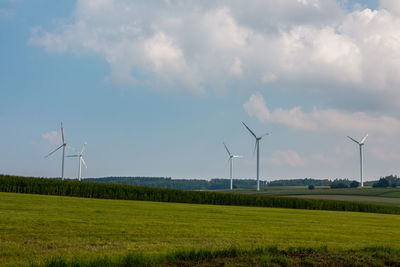 Windmills on field against sky