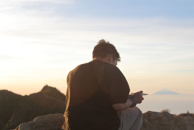 Rear view of people on mountain against sky during sunset