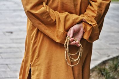 Midsection of man holding religious bead