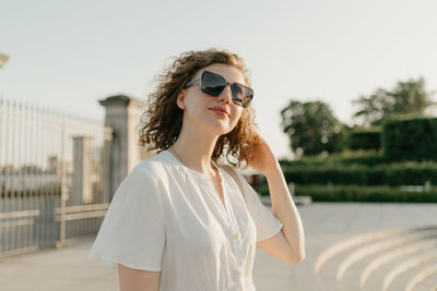 Portrait of young woman wearing sunglasses standing on road